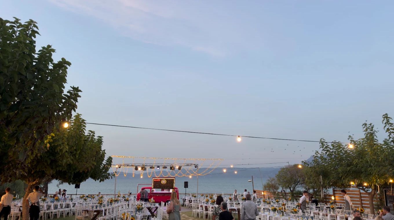 Tables in a garden with string lights, by the sea, at Sabbia.